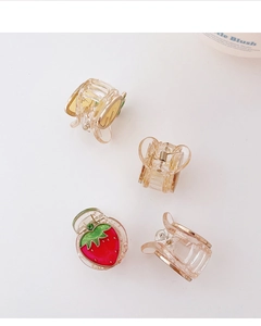 Dettaglio di mini mollette per capelli a fragola e clip in acrilico trasparente su bianco