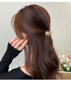 Detail view of a beige heart hair claw clip styled on a semi-tied hairstyle with curly hair