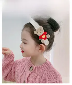 Detailed view of kids white knitted headband with cute brown bear wearing heart sweater