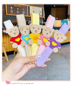 Detail of five colorful embroidered teddy bear hairbands with soft knit texture