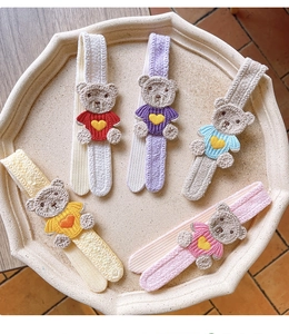 Set of five colorful embroidered bear hairbands in soft coral fleece on a tray