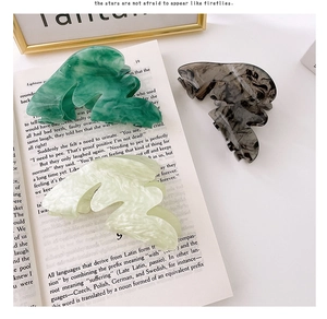 Vue détaillée des pinces à cheveux irrégulières en acétate avec texture marbrée d'encre