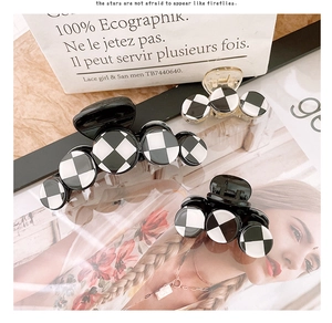 Detail view of large checkered hair claw clips with monochrome grid patterns and glossy finish