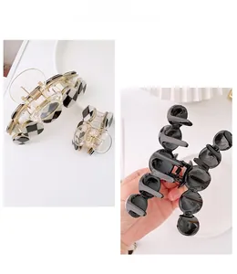 Detail showing checkerboard pattern hair claw clips and black glossy sphere design grips