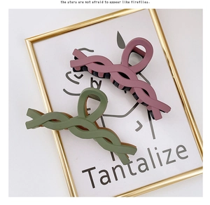 Close-up of matte twist hair claws in dusty pink and sage green colors with spiral design
