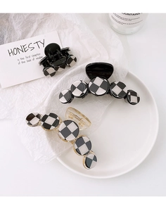 Detailed view of large black and white checkerboard round hair claws on white display plate