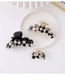 Macro detail of checkered hair claw clips in black and white pattern on white ceramic plate