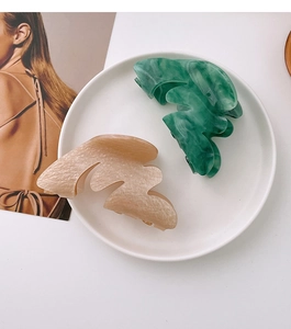 Détail des pinces à cheveux irrégulières marbrées vertes et nacrées sur une assiette en céramique
