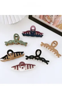 Close-up of woven plastic hair claws in six diverse colorways on a white surface