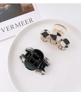 Close-up of black and amber hair claws with checkerboard pattern on white tray