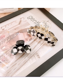 Detail view of large checkered shark hair clips in black and white acrylic on a magazine