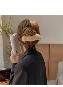 Vue détaillée d'une pince à cheveux en peluche beige portée dans un cadre intérieur chaleureux