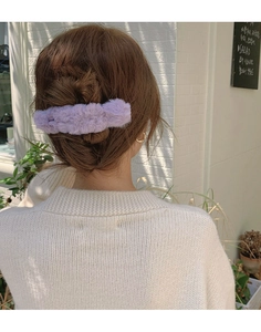 Pince à cheveux élégante en fausse fourrure lavande, portée dans un décor extérieur
