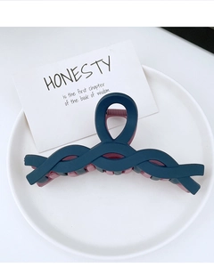 Detail of matte blue and pink plastic hair claw clip on white ceramic background