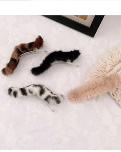 Détail de pinces à cheveux en peluche avec motifs léopard et vache sur nappe en dentelle