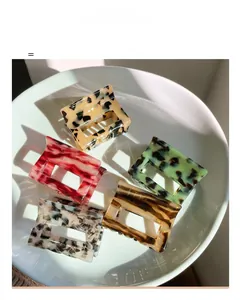 Set of five tortoiseshell acetate hair claws in various colors on a ceramic tray