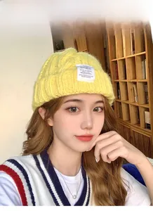 Close-up of bright yellow chunky knit beanie with a decorative white woven label