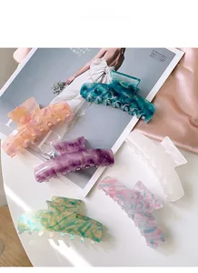 Assorted cellulose acetate hair claw clips in marble patterns on pink silk background