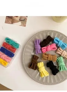 Dettaglio di elastici in peluche colorati in un piatto di ceramica per lo styling dei capelli