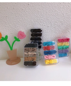 Primo piano di quattro scatole di elastici per capelli colorati ad alta elasticità su bianco