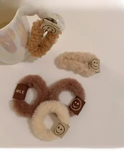Détail de chouchous et barrettes en laine d'agneau pelucheuse avec étiquettes sourire