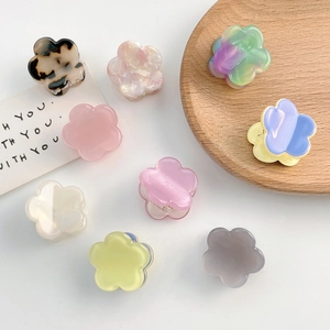 Mini pinces à cheveux florales en couleurs pastel variées sur un fond minimaliste