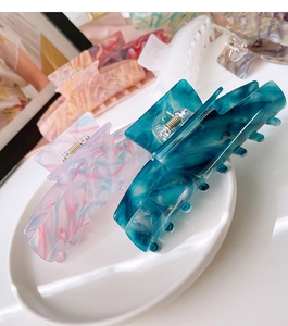 Close-up of T-shaped acetate claw clips in marble patterns on elegant silk fabric
