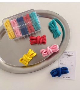Dettaglio di cinque elastici per capelli colorati in una scatola portaoggetti trasparente