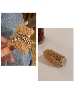 Vue détaillée de pinces à cheveux en peluche Teddy avec ours à nœud écossais et motif smiley