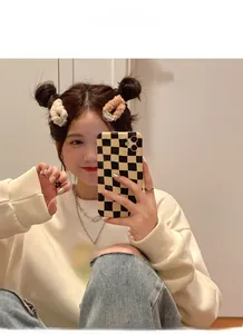 Détail d'élastiques à cheveux en peluche avec smiley en beige et café en selfie