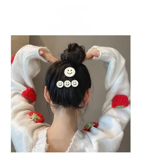 Dettaglio di fermagli per capelli con smiley bianco e nero indossati su uno chignon