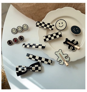 Dettaglio di fermagli per capelli a scacchi e smiley in nero, bianco e beige