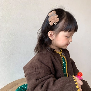 Pince à cheveux ours en peluche marron avec nœud à carreaux sur une jeune fille