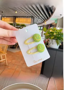 Close-up of yellow fabric hair clips with green knit smiley face buttons on display card