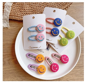 Detailed view of colorful fabric smiley face hair clips on white ceramic display