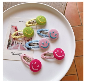 Close-up of five colorful fabric-wrapped BB hair clips with embroidered smiley faces