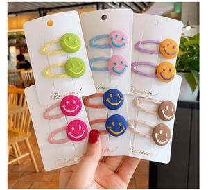 Detailed view of colorful fabric smile face hair clips with embroidered patterns for girls