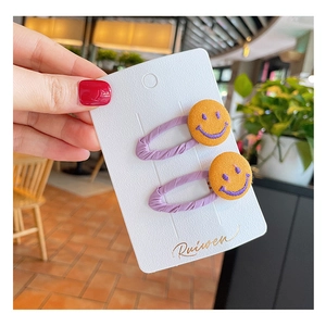 Close-up of kids' purple fabric-wrapped hair clips with yellow smiley face button details