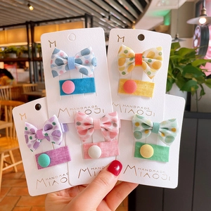 Close-up of five pairs of colorful floral and polka dot fabric bow hair clips for kids