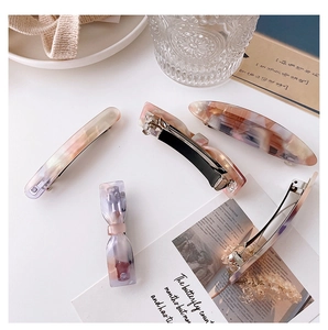 Detailed view of acetate spring hair clips with marble texture in soft mermaid tones