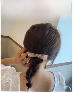 Rear view of a mermaid purple acetate bow hair clip styled on a braided hairstyle