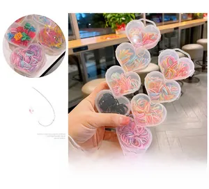Détail d'une boîte en forme de cœur avec des élastiques et barrettes colorés pour enfants