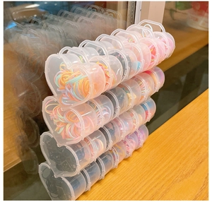 Vue détaillée de boîtes de rangement en forme de cœur avec des élastiques à cheveux colorés