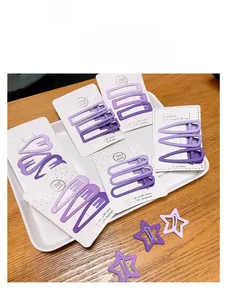 Macro di fermagli per capelli viola opachi in forme geometriche su carta bianca
