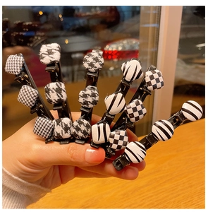 Détail de pinces à cheveux à motifs damier et pied-de-poule avec base en métal noir