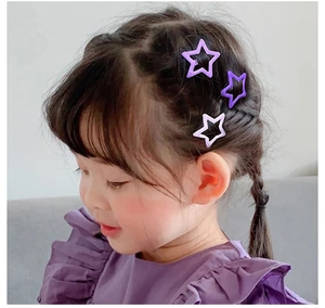 Dettaglio di una bambina con tre fermagli per capelli viola a forma di stella