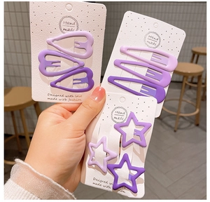 Dettaglio di fermagli per capelli viola opachi a forma di stella e cuore su carta