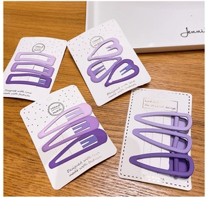 Dettaglio di fermagli per capelli viola opachi in forme geometriche su carta bianca