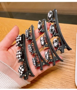 Détail de quatre barrettes à motifs damier et pied-de-poule sur une surface en bois