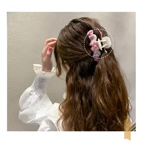 Détail d'une pince à cheveux avec nœuds roses portée sur des cheveux ondulés de style